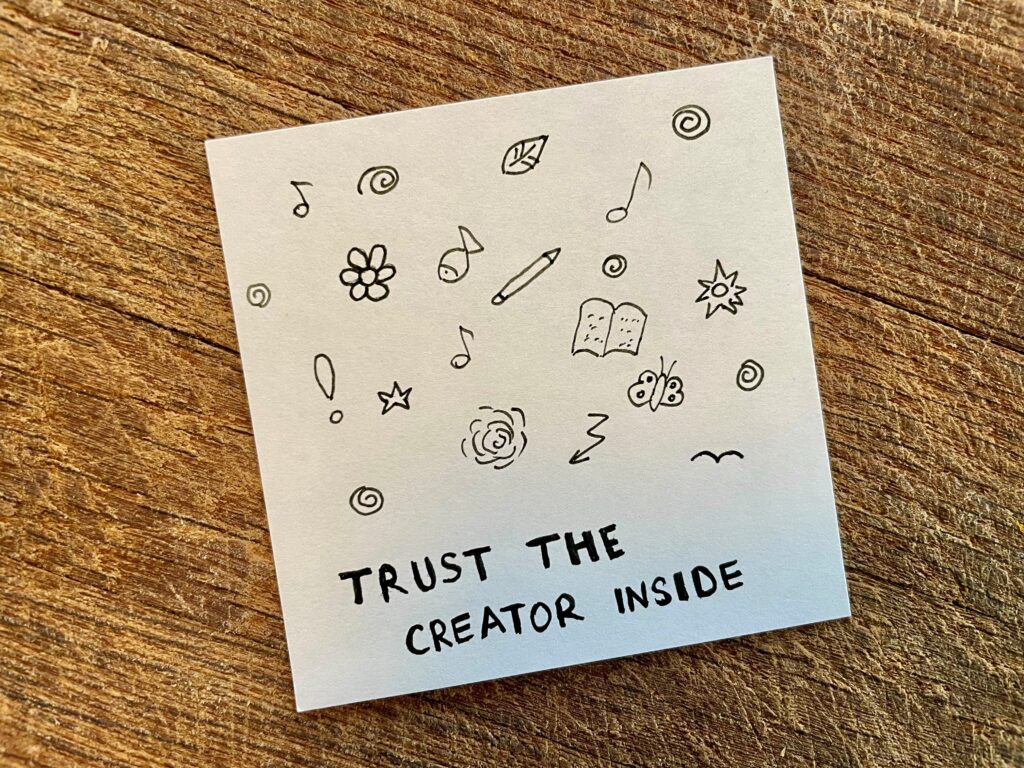 A handwritten card in black ink saying "Trust the creator inside" by the author Adriana Kantcheva 